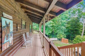 Eine Holzdiele mit Veranda, Schaukelstühlen und einem Gemälde.
