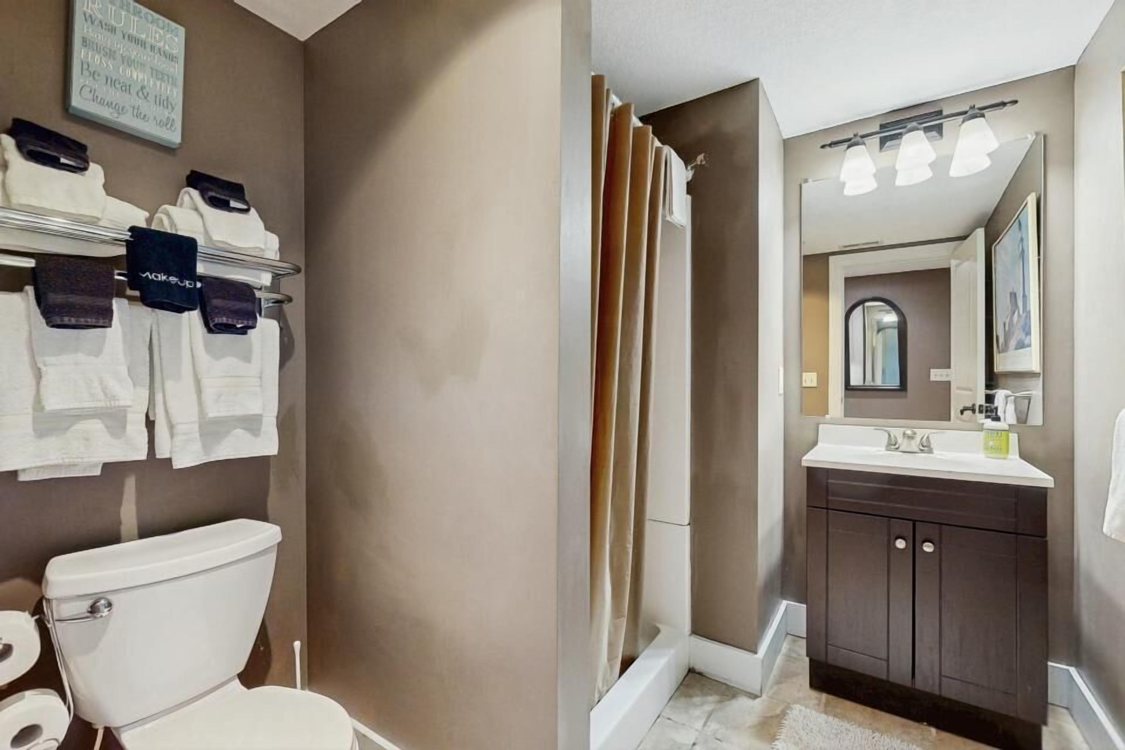 Un baño con inodoro, cortina de ducha, lavabo y espejo.