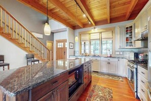 Eine geräumige Küche mit Granit-Arbeitsplatte, einer Holztreppe und weißen Schränken.