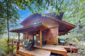 A wooden cabin with a covered porch, a grill, and potted plants. - Eagles Wing Lodge | Game Room, Firepit, Dazzling Sunset Views | Near Downtown (Asheville)