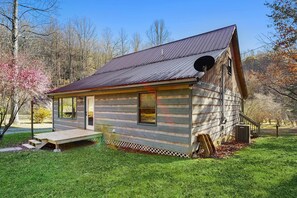 Eine kleine Holzhütte mit einem Metalldach, einer Veranda und einer kleinen Terrasse.