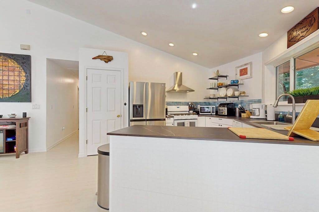 A modern kitchen with a central island, stainless steel appliances, and a view of the outdoors.