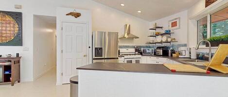 A modern kitchen with a central island, stainless steel appliances, and a view of the outdoors.