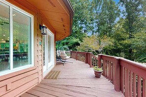 A wooden deck with a railing, a hanging chair, and a potted plant. - Circle House in the Smoky Mountains (Whittier)