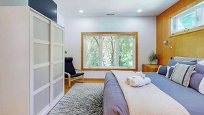 A bedroom with a bed, a chair, a window, and a wardrobe. - Dog-friendly downtown retreat with 2 kitchens & large fenced yards (Brevard)