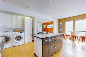 A modern kitchen with built-in appliances, a dining area with a view, and a small island with stools.