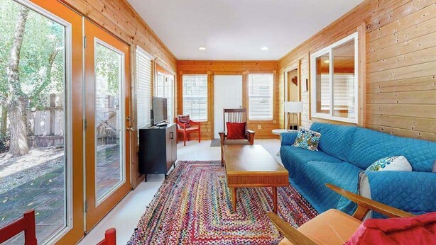 A cozy living room with a blue sofa, a coffee table, and a TV. - Dog-friendly downtown retreat with 2 kitchens & large fenced yards (Brevard)