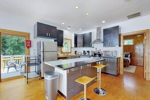 A modern kitchen with a central island, stainless steel appliances, and a view to the outside.