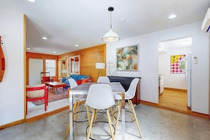 A dining area with a table and chairs, a hanging light fixture, and a wooden accent wall.