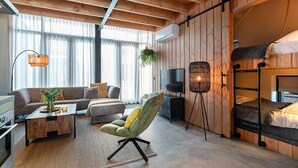 Una sala de estar acogedora con sofá, sillón, televisión y litera.