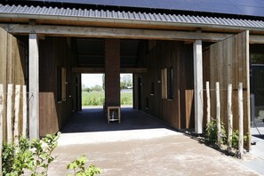 A covered stable with open doors, a central pillar, and a paved entrance. - Lennepserf - De Horstjes (Veessen)