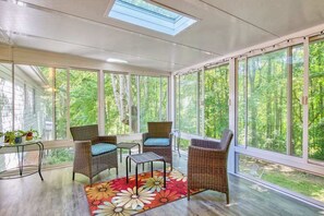 A sunroom with wicker furniture, large windows, and a skylight. - Dog-friendly home with large yard, lawn games, firepit, screened porch, & AC (Asheville)