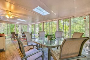 A sunlit room with a glass table, chairs, and a ceiling fan. - Dog-friendly home with large yard, lawn games, firepit, screened porch, & AC (Asheville)