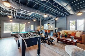 A spacious living area with a foosball table, a sofa, and a coffee table. - Spacious mountain view lodge with  firepit, game room and incredible views (Black Mountain)