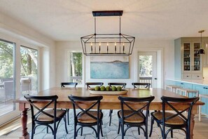A dining area with a large wooden table, black chairs, a central light fixture, and a painting on the wall. - Spacious mountain view lodge with  firepit, game room and incredible views (Black Mountain)