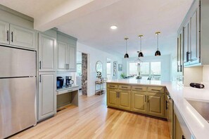 A modern kitchen with light wood flooring, a central island, and pendant lighting. - Spacious mountain view lodge with  firepit, game room and incredible views (Black Mountain)