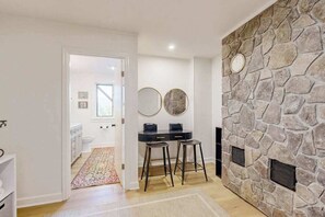 A room with a stone fireplace, a white door leading to another room, and two stools. - Spacious mountain view lodge with  firepit, game room and incredible views (Black Mountain)