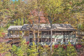 Ein zweistöckiges Haus mit Balkon, umgeben von Bäumen im Herbstlaub.