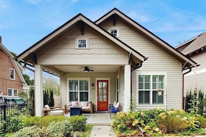 A two-story house with a covered porch, a front door, and a small window. - Downtown Delight | Luxury home, walk to Main Street, bike to trails (Brevard)