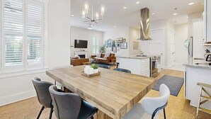 A modern kitchen with a wooden island, built-in appliances, and a large dining table. - Downtown Delight | Luxury home, walk to Main Street, bike to trails (Brevard)