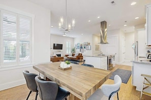 A modern kitchen with a wooden island, built-in appliances, and a large dining table. - Downtown Delight | Luxury home, walk to Main Street, bike to trails (Brevard)