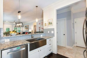 A modern kitchen with granite countertops, stainless steel appliances, and a double sink. - Charming home with screened porch, private yard, fireplace, & fast WiFi (Black Mountain)