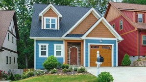 Une maison à deux étages avec un garage à l’avant, une boîte aux lettres et une pelouse bien entretenue.