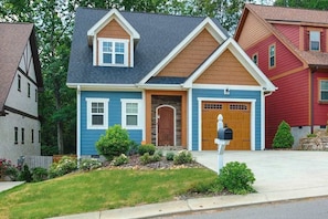 A two-story house with a front garage, a mailbox, and a well-maintained lawn. - Charming home with screened porch, private yard, fireplace, & fast WiFi (Black Mountain)