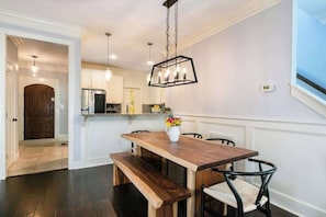 A dining area with a wooden table, benches, and chairs. - Charming home with screened porch, private yard, fireplace, & fast WiFi (Black Mountain)