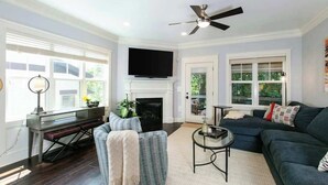 Un salon avec une cheminée, un téléviseur, un ventilateur de plafond et un canapé.