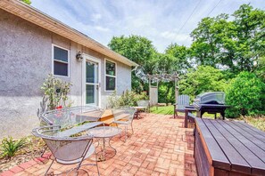 Un patio con mobiliario exterior, una parrilla y una pérgola.