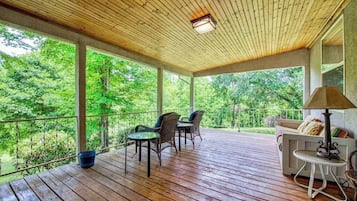 Un espace extérieur abrité, doté d’un plancher en bois, d’un canapé, de deux fauteuils et d’une table.