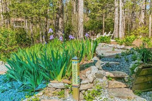 A garden with a wooden signpost, a stone pathway, and a wooden fence.