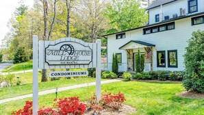 A sign for Mill House Lodge Condominiums with a house in the background. - Lakeview pet friendly studio with pool, fire pit, canoes & paddle boats, & WiFi (Flat Rock)