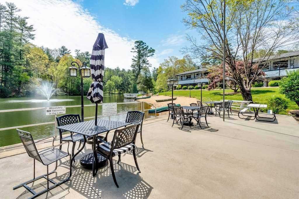 Patio esterno con tavoli e sedie, una fontana e un cartello che vieta il nuoto nel lago.