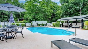 A swimming pool with lounge chairs and umbrellas, surrounded by greenery. - Lakeview pet friendly studio with pool, fire pit, canoes & paddle boats, & WiFi (Flat Rock)