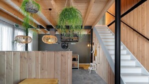 A modern interior with wooden walls, a staircase, and hanging plants. - Lennepserf - De Pinkels (Veessen)