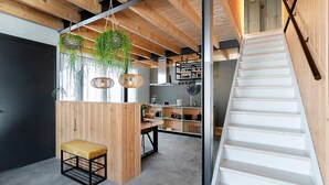 A modern interior with a wooden staircase, a dining area with a bench, and hanging plants. - Lennepserf - De Pinkels (Veessen)