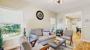 Ein Wohnzimmer mit Sofa, Sesseln, einem Couchtisch und einem Essbereich mit Tisch und Stühlen.
