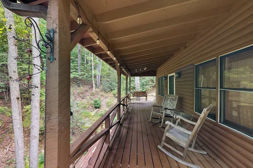 A wooden deck with a railing, a bench, and a rocking chair.