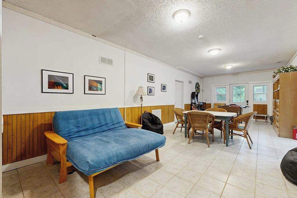 Une pièce avec un canapé bleu, une table à manger avec des chaises et des tableaux encadrés accrochés au mur.