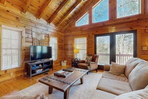 Ein Interieur einer Holzhütte mit Fernseher, Sofa und Couchtisch.