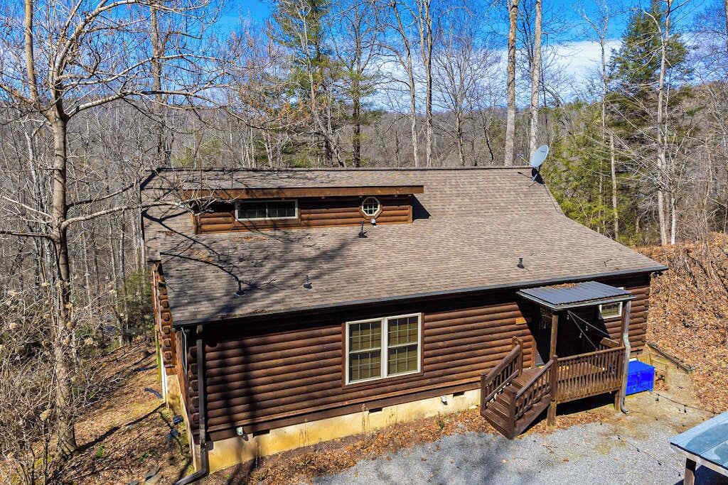 A log cabin with a dormer window, a small porch, and a satellite dish.