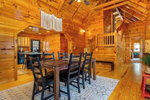 Ein Interieur einer Holzhütte mit Essbereich, Küche und einer Treppe.