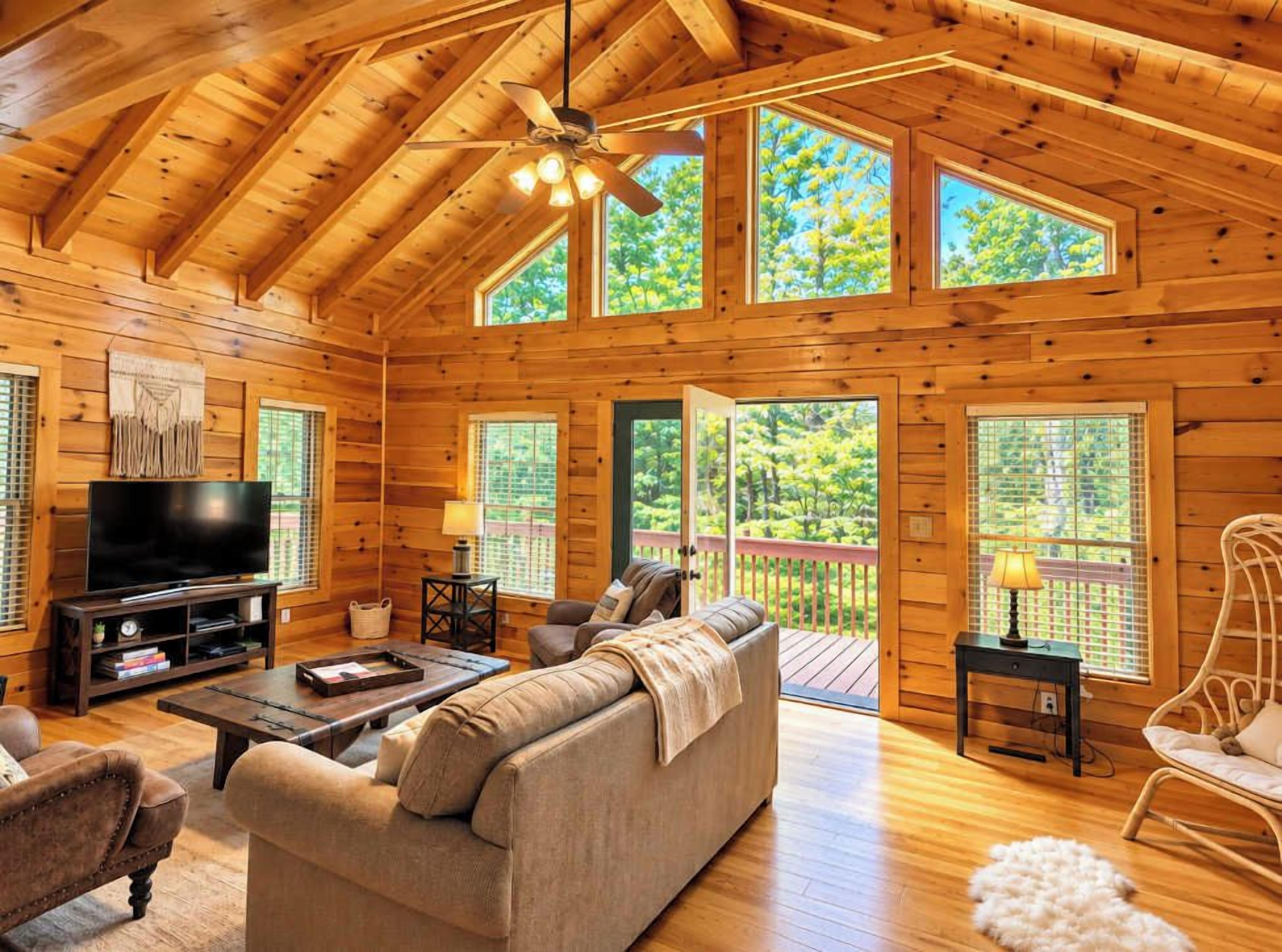 A log cabin interior with a television, sofa, and dining area.