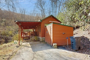 Eine kleine Holzhütte mit Veranda, Mülleimer und einem Schild, das auf ein befestigtes Gelände hinweist.