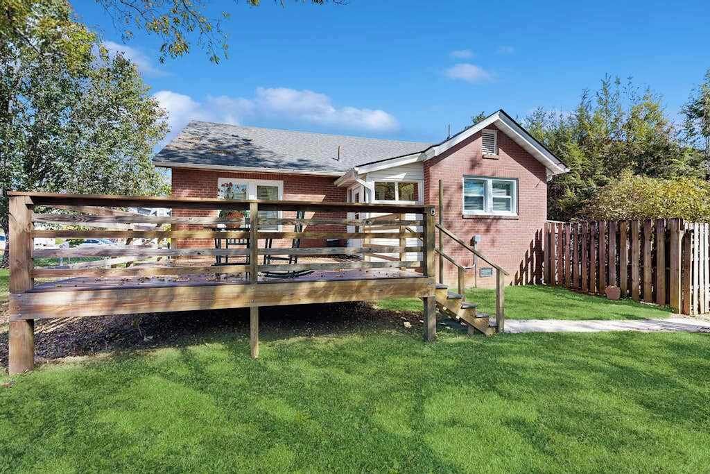 Une maison à deux étages avec une terrasse en bois et une cour clôturée.