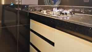 A modern kitchen with a central island, black and white cabinetry, and a logo on the wall.