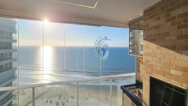 A balcony with a view of the sea and a logo on the glass.