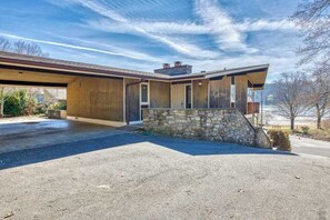 Ein modernes Haus mit rustikalem Steinfundament, einer großen Garage und einer überdachten Auffahrt.